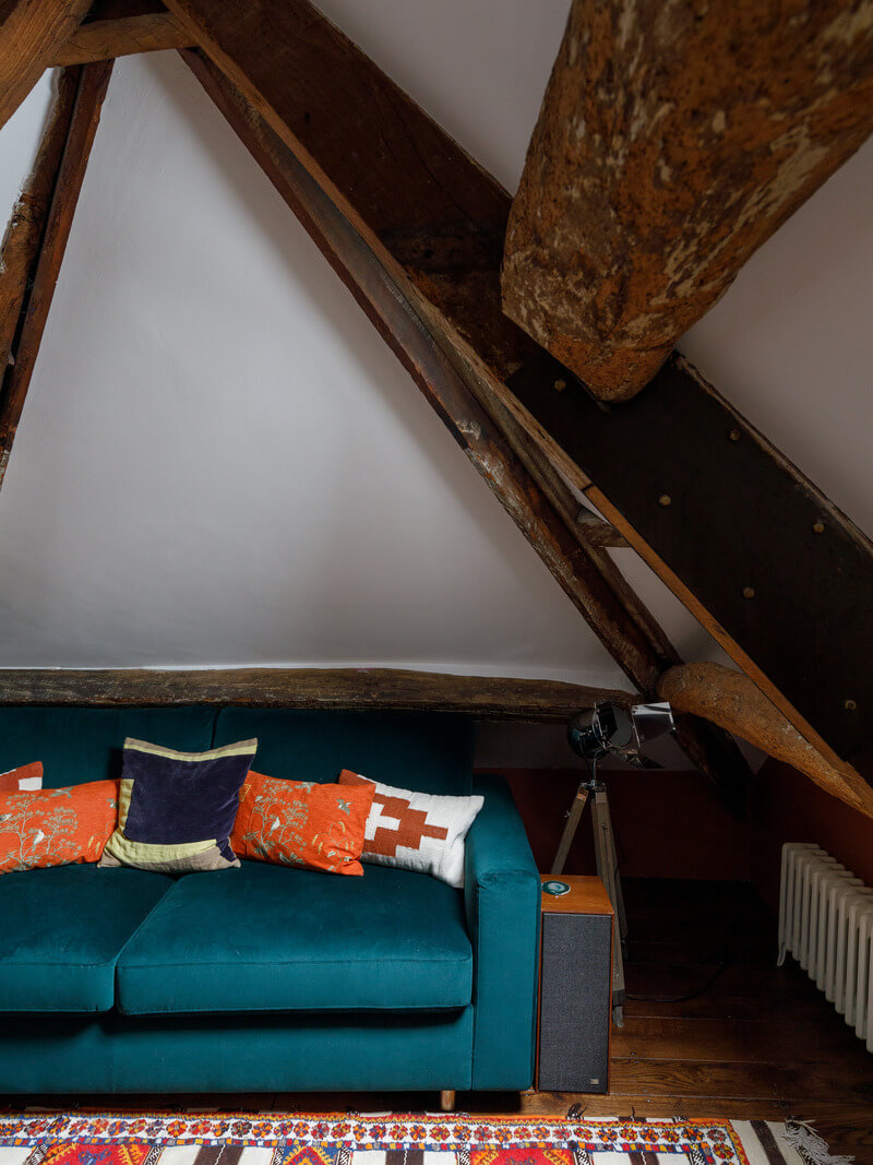 attic bedroom with emerald sofa
