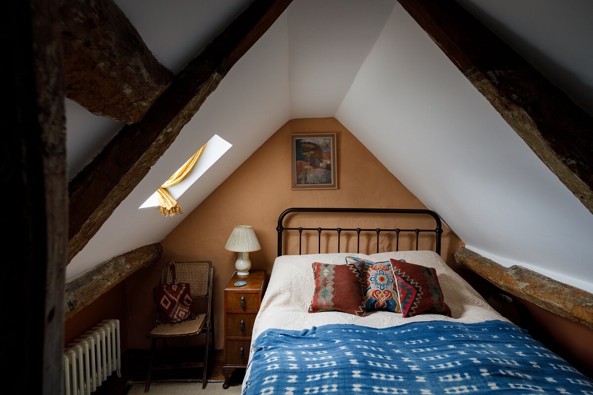 attic bedroom with terracotta brown walls and wooden beams