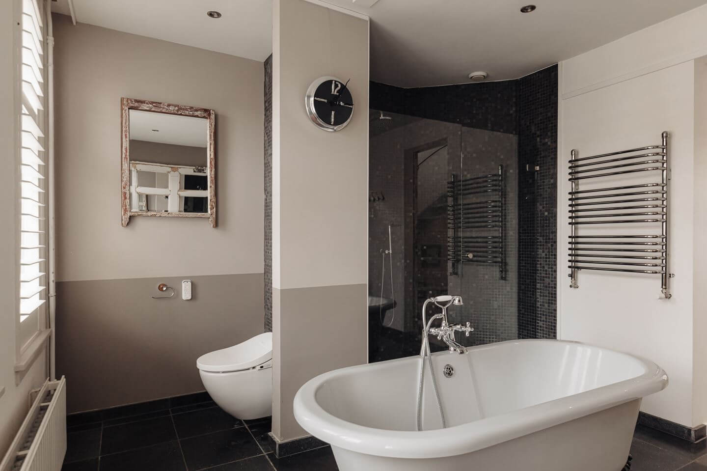 bathroom with freestanding bath and black tiled shower