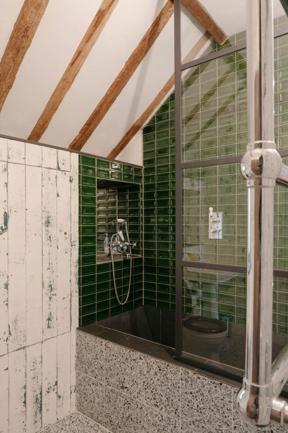 bathroom with pitched ceiling wooden beams and green tiles