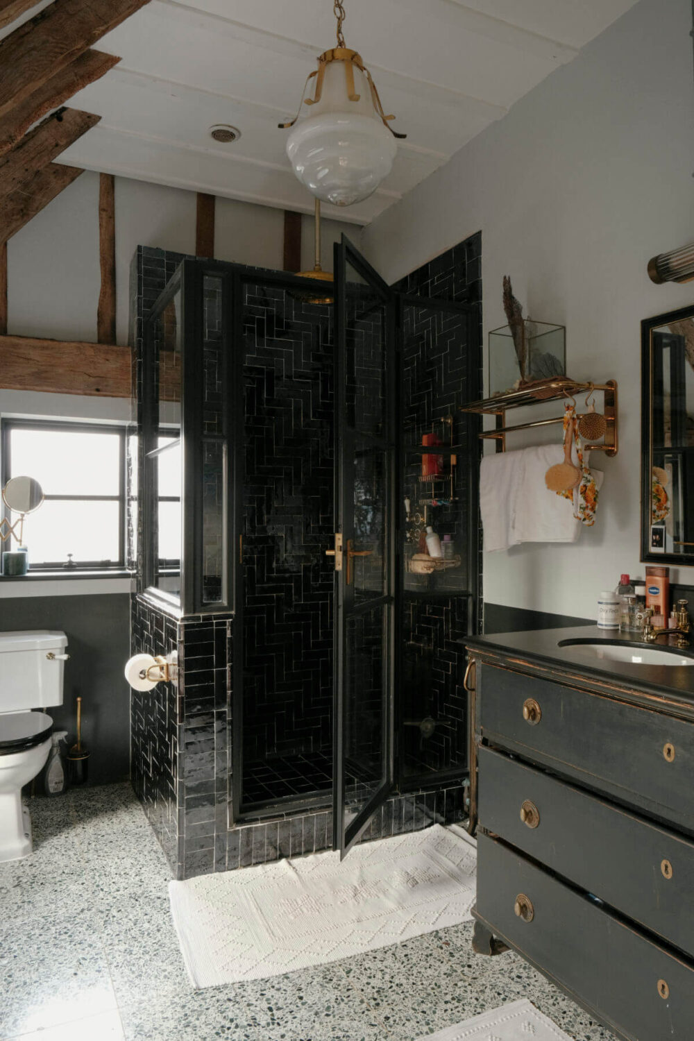 bathroom with wooden beams and black tiles in shower