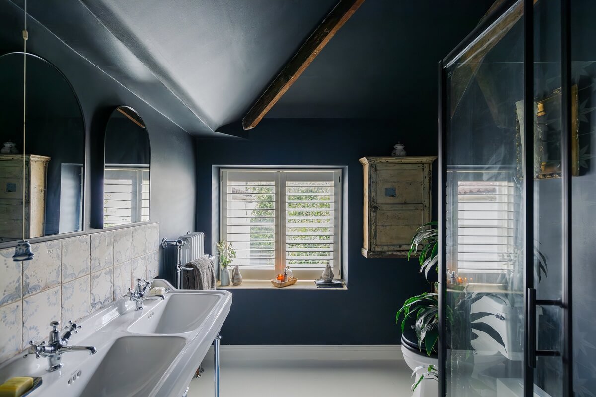 blue bathroom with double sink and wooden beam