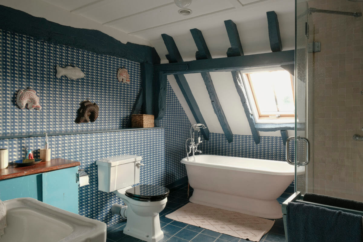 blue bathroom with slanted ceiling and freestanding bath