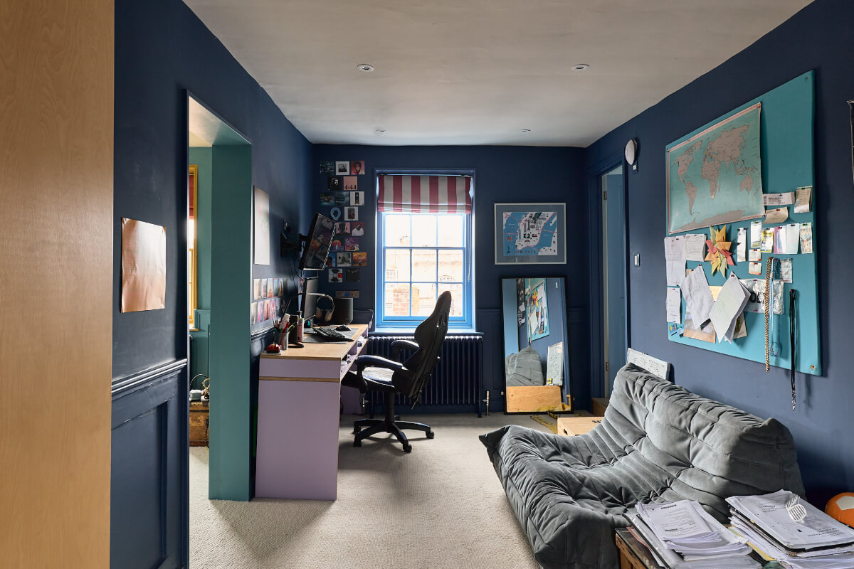 dark blue bedroom with desk and sofa