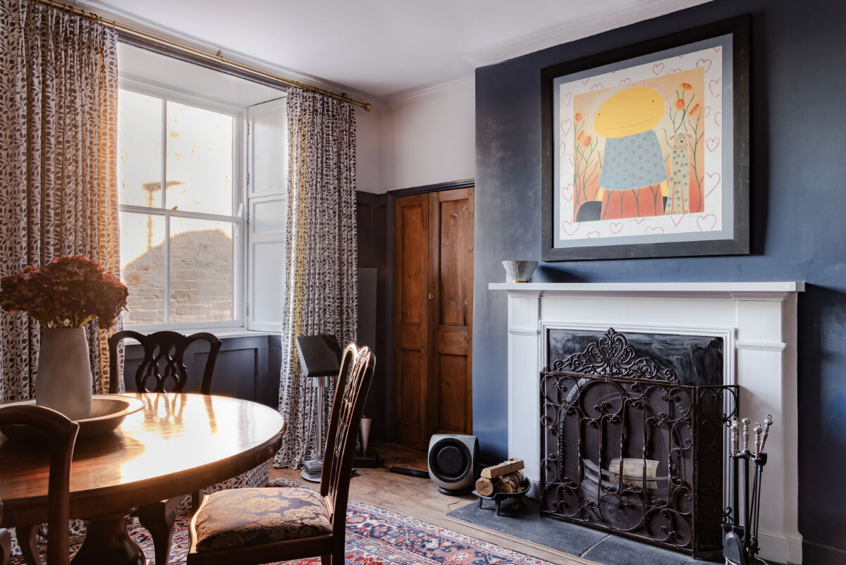dining room with dark blue walls round table and fireplace