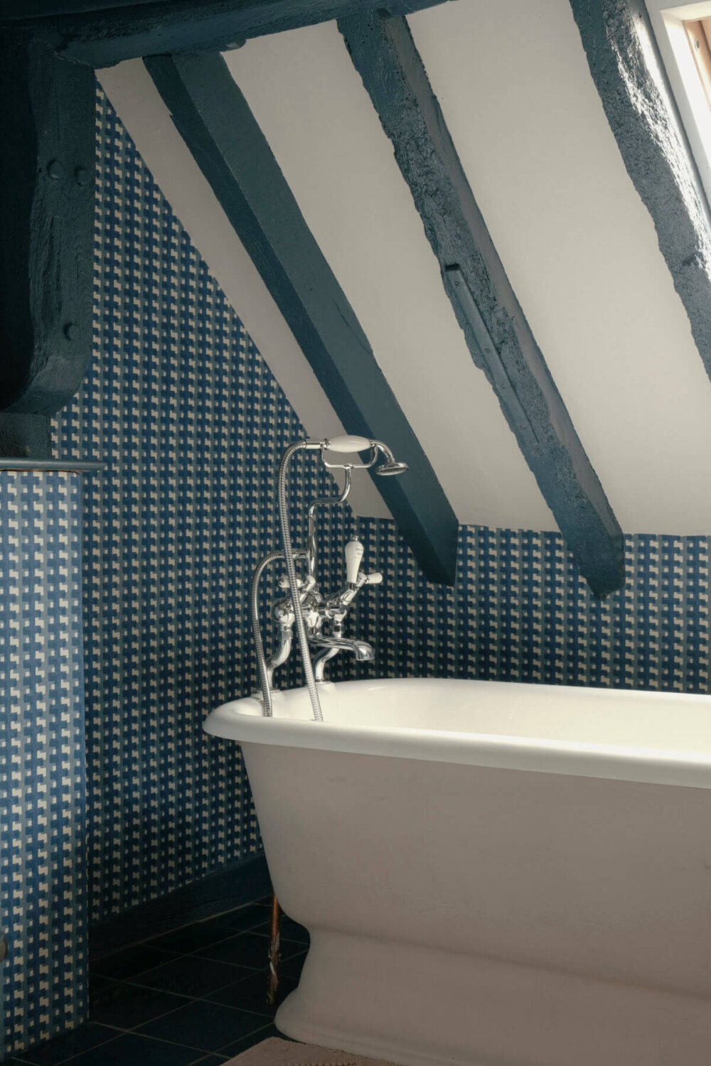 freestanding bath in blue bathroom with slanted ceiling and blue painted beams