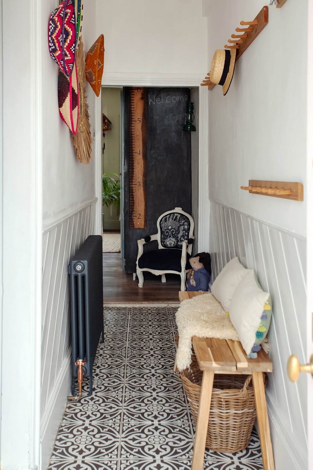narrow entryway with bench and hooks and black and white floor tiles nordroom
