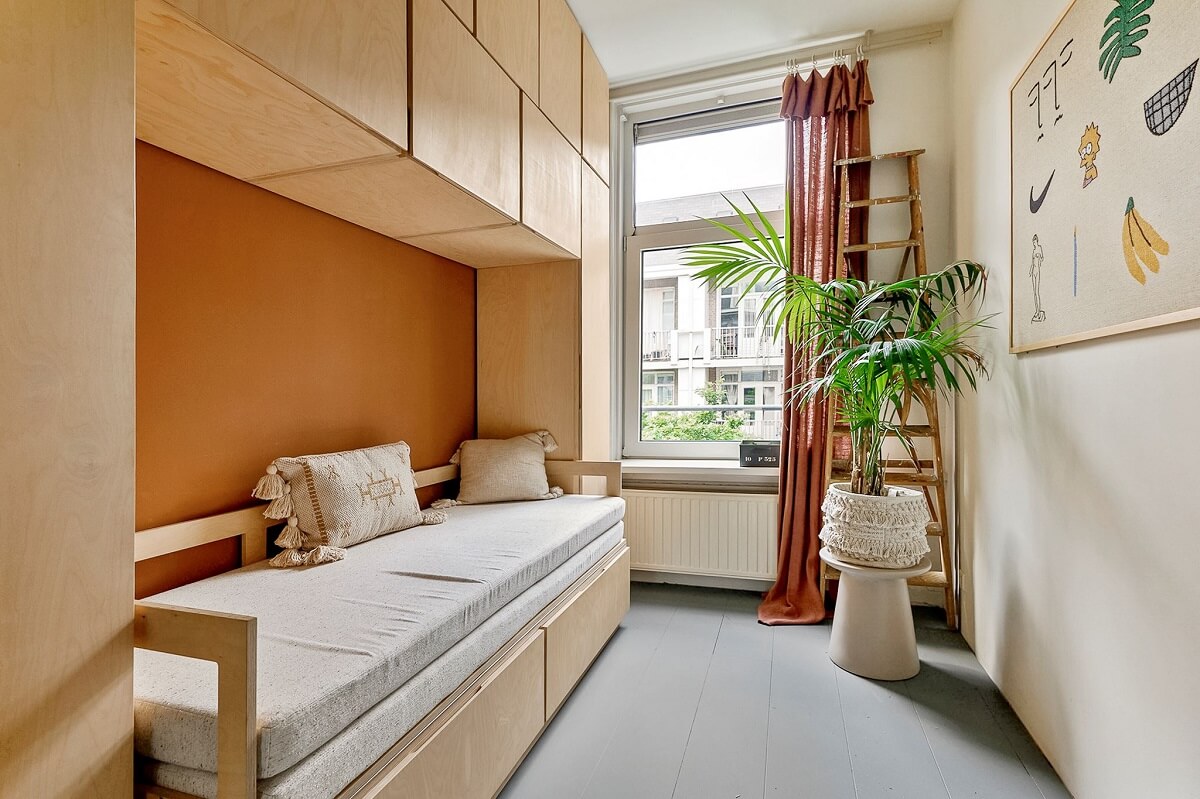 small bedroom with orange feature wall and wall mounted storage