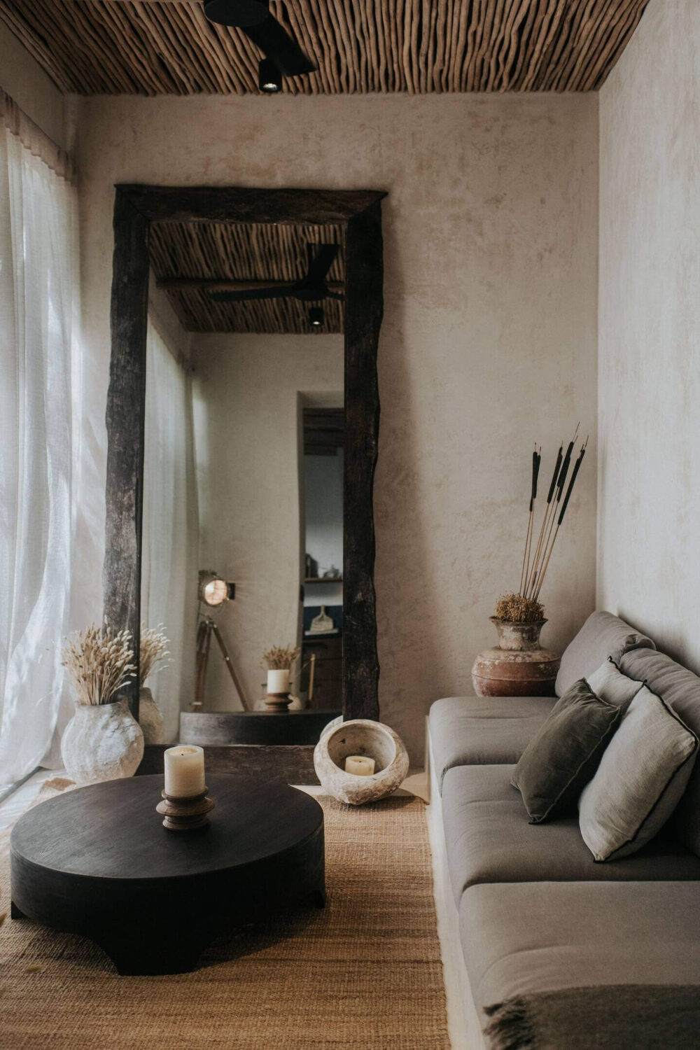 small-sitting-room-gray-sofa-round-black-coffee-table-large-mirror-wooden-ceiling-nordroom